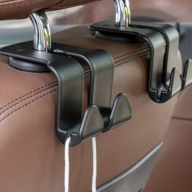 A close-up view of two black metal hooks designed to attach handbags or coats to a car headrest.
