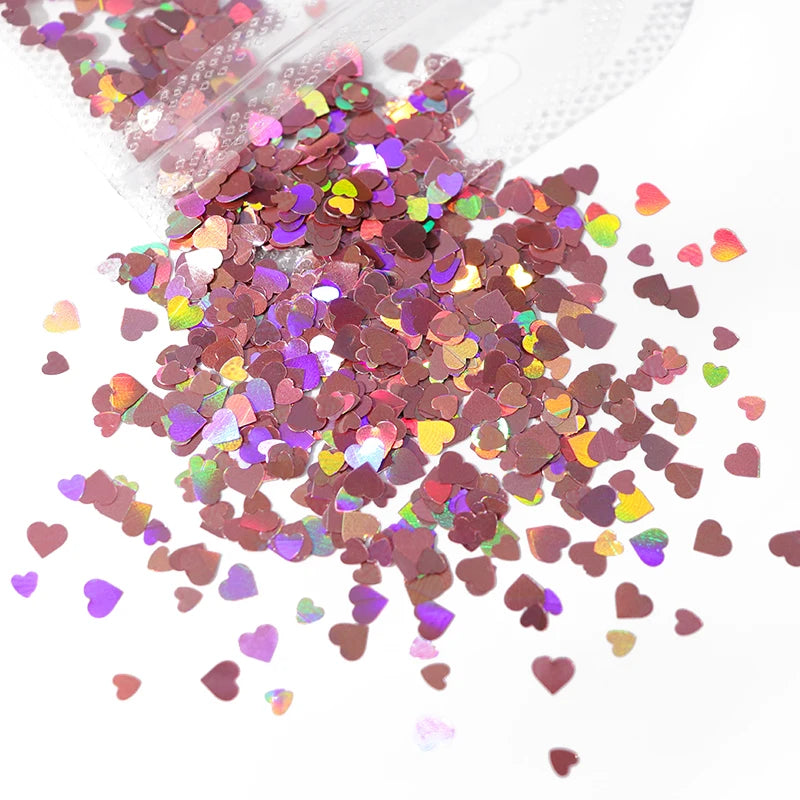 A pile of shiny holographic star sequins in various shades of pink and purple scattered on a white surface.