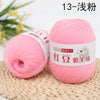 Pink fine yarn for knitting and crochet displayed next to a plant on a woven mat