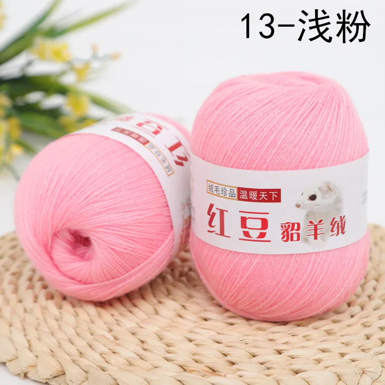 Pink fine yarn for knitting and crochet displayed next to a plant on a woven mat
