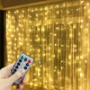 A hand holds a remote control for USB LED curtain string lights, illuminating a sheer golden curtain.