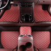 Interior view of a car with red quilted leather floor mats and a center console.