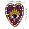 A heart-shaped embroidered patch featuring a gold sunburst and an eye design surrounded by purple and white beads.