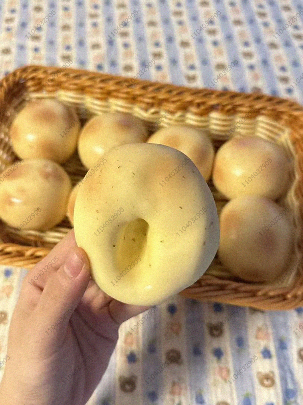Eine Hand hält einen gelben knackigen Kartoffel-Stressball-Fidget-Spielzeug in einem geflochtenen Korb.