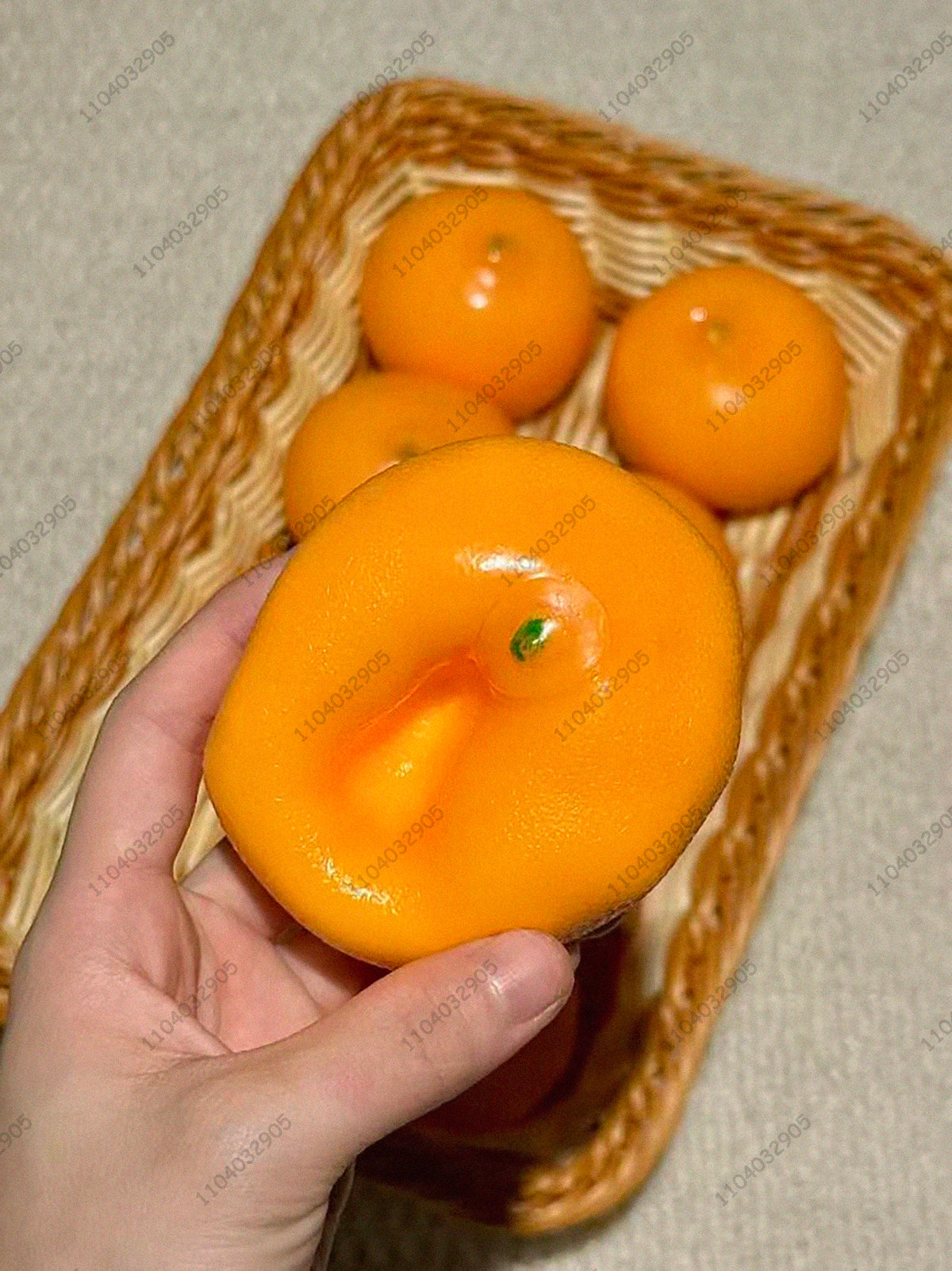 Eine Hand hält einen leuchtend orangefarbenen knackigen Kartoffel-Stressball, umgeben von ähnlichen Bällen in einem geflochte