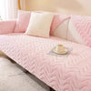 A pink plush sofa cushion mat with white accent pillows and a teacup resting on the surface.