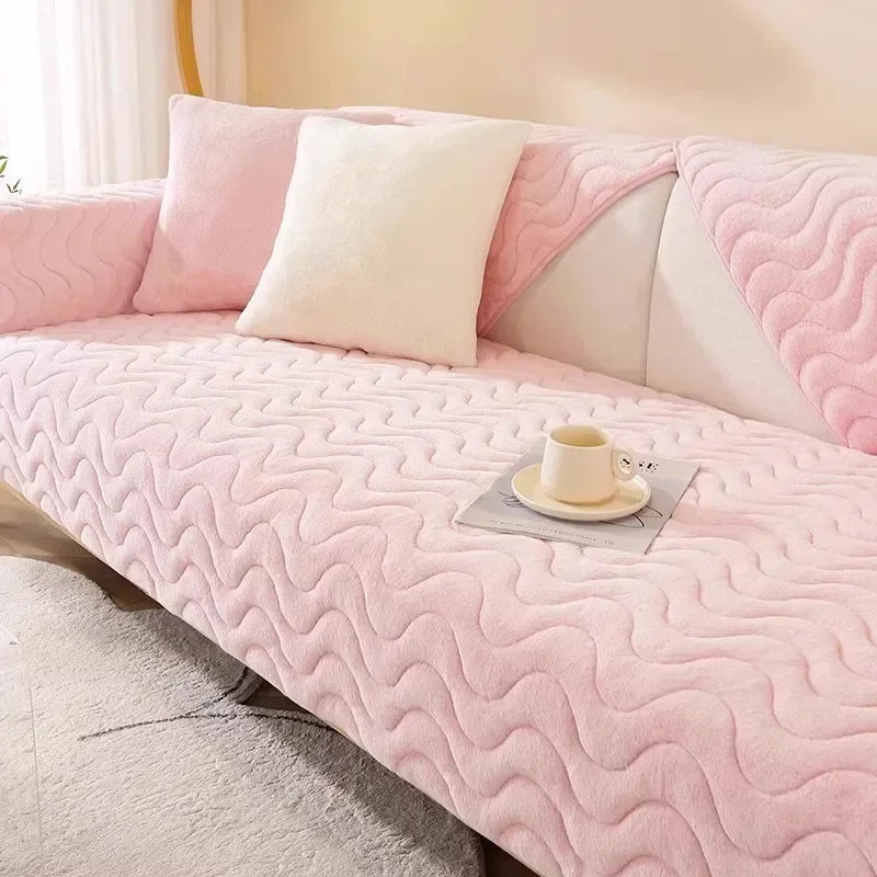 A pink plush sofa cushion mat with white accent pillows and a teacup resting on the surface.