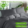 Graue Bambus-Duvetcover-Set auf einem Bett mit grünen Pflanzen im Hintergrund.
