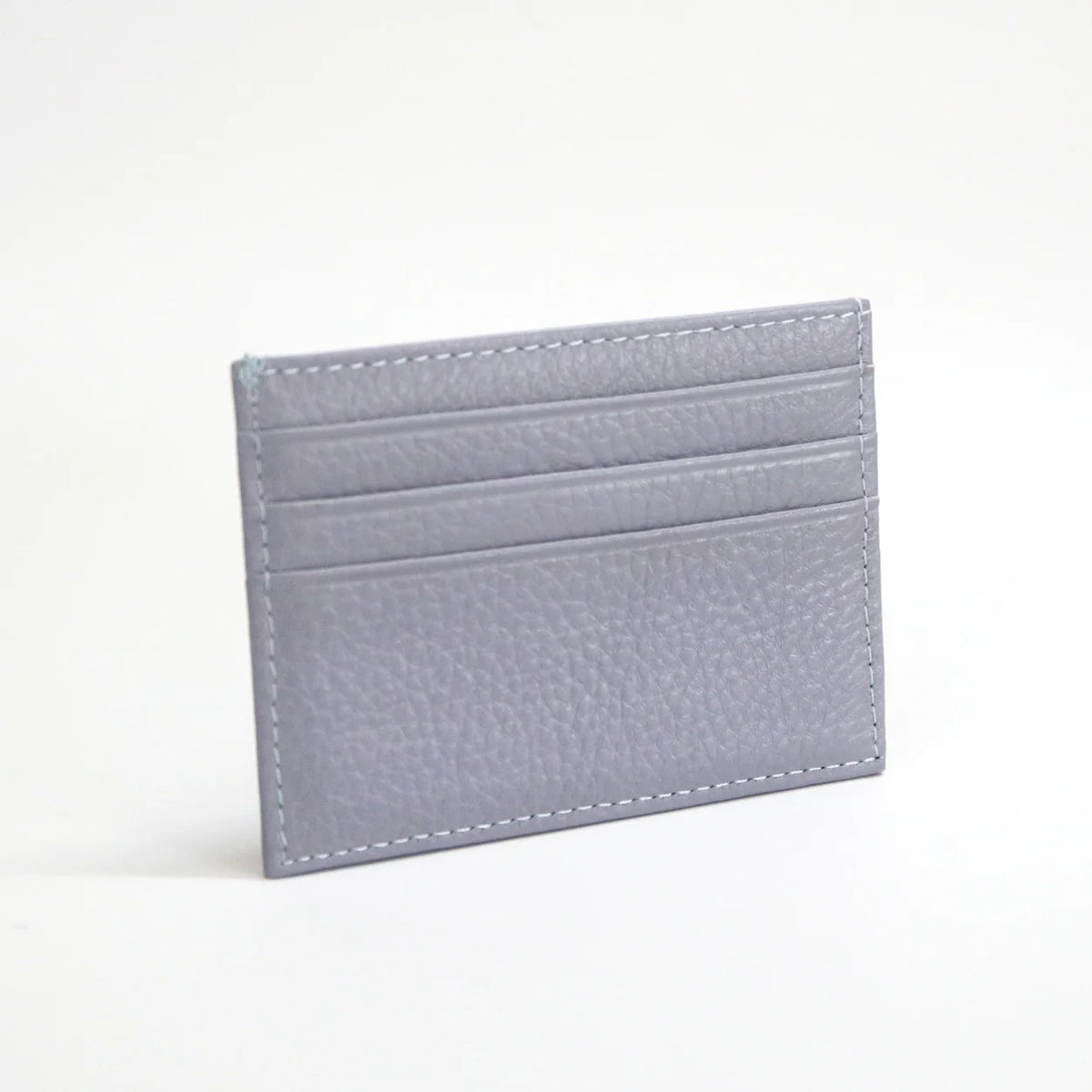 Porta tarjetas de cuero genuino gris y delgado con múltiples líneas cosidas horizontales.