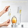 A hand is applying a drop of oil to a spring roller massage comb, demonstrating its use for essence absorption.