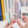 A hand holds a pink portable scissor with a cat paw design, demonstrating the stainless steel cat paw portable scissors.