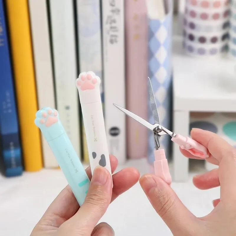 A hand holds a pink portable scissor with a cat paw design, demonstrating the stainless steel cat paw portable scissors.