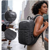 A woman wearing a black laptop backpack walks in the rain, demonstrating its water-resistant and tear-resistant features.