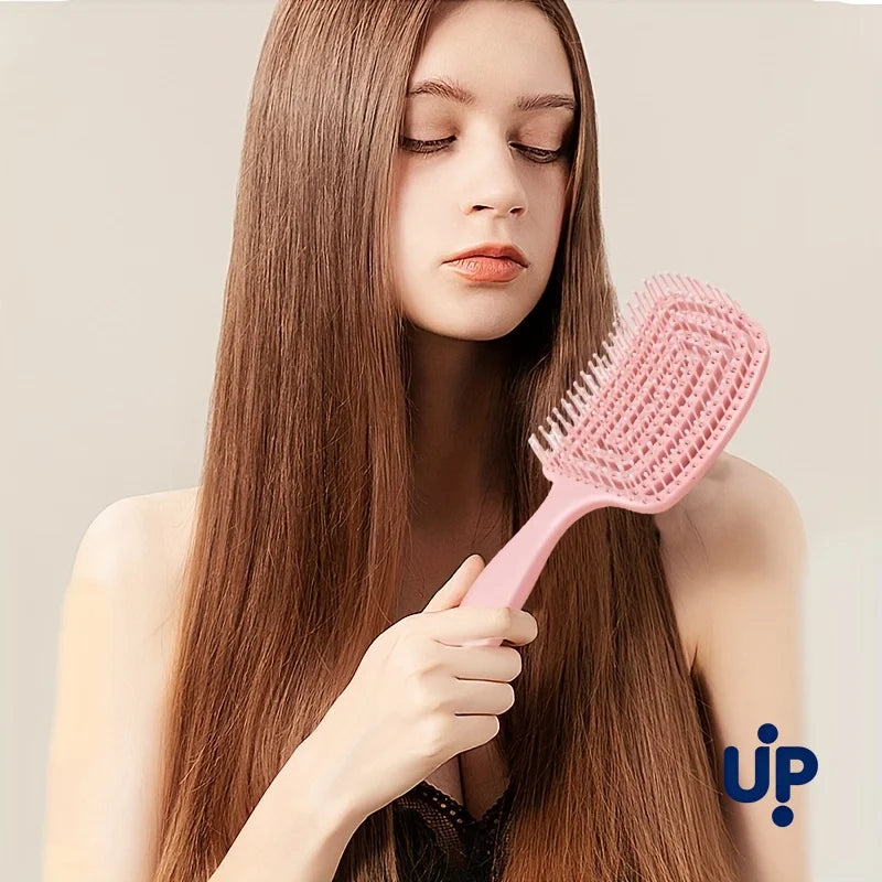 A woman holds a pink volumizing detangling hair comb against her long brown hair.