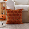 An orange plush throw pillow covered in repeating green pumpkin patterns resting on a gray rug.