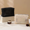 A black lace mesh makeup bag is displayed next to a cream-colored lace fabric makeup bag on a white surface.