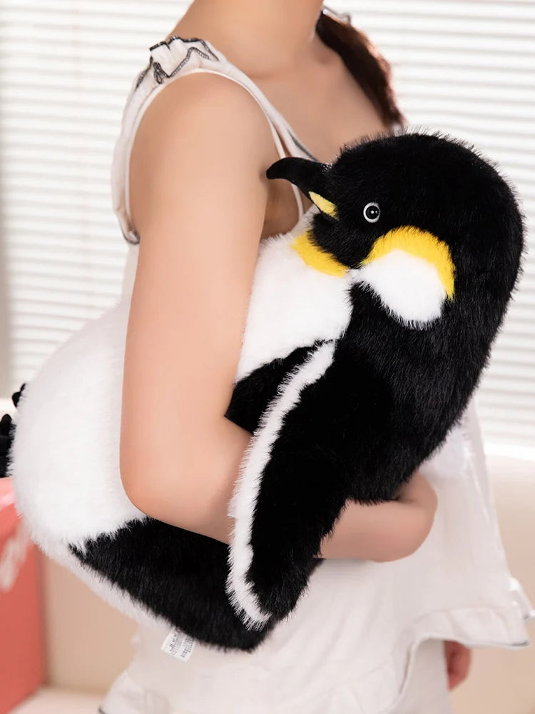 A black and white penguin plush toy is held by a person, showing its soft texture and design.