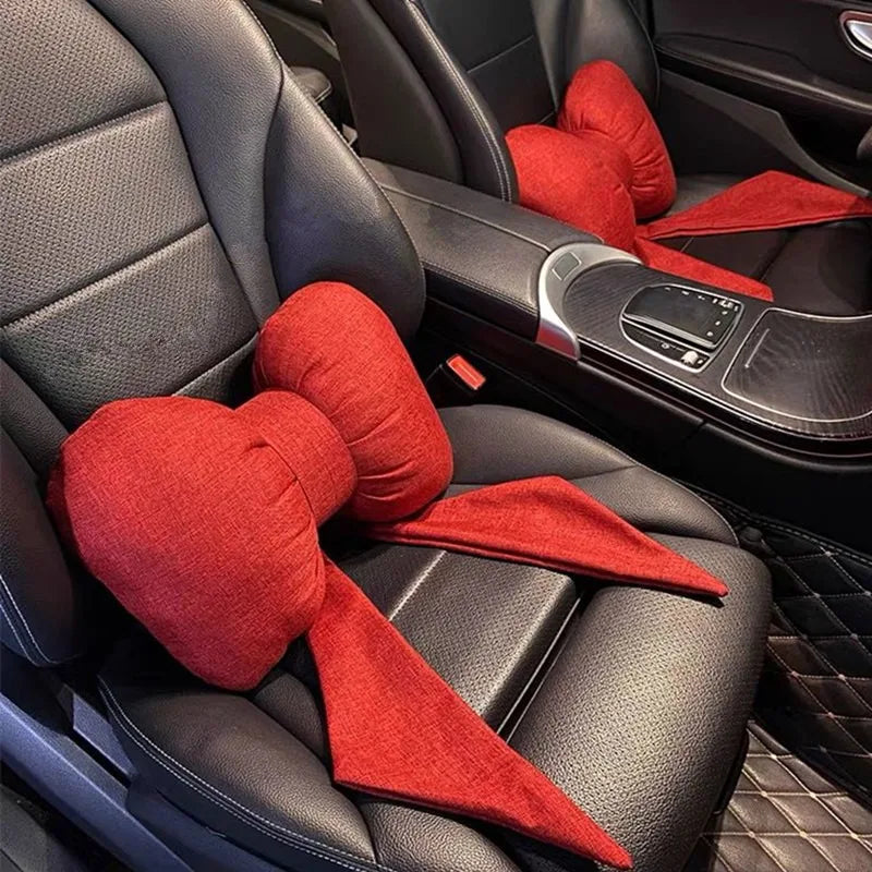 Red butterfly bow tie neck pillows with cotton and linen covers placed in a car seat interior.