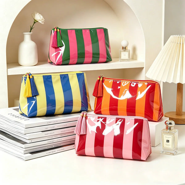 Collection de sacs cosmétiques colorés à rayures et franges exposés sur une étagère à côté d'une lampe.