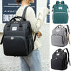 A woman is holding a black backpack diaper bag with a changing mat and various color options.
