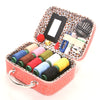 A portable faux leather sewing kit in a pink box containing various needles, thread, and tools.