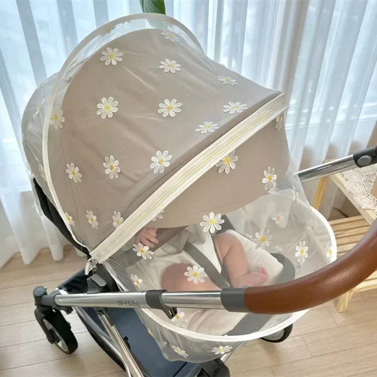 A beige universal mosquito net cover for a baby stroller or crib, shown in a daylight setting.