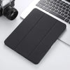 A black Retro Marble iPad Pro 12.9 case with a pencil holder resting on a white surface next to a silver camera and a laptop.