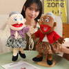A hand puppet set featuring two characters, one with gray hair and another with brown skin, displayed on a green surface.