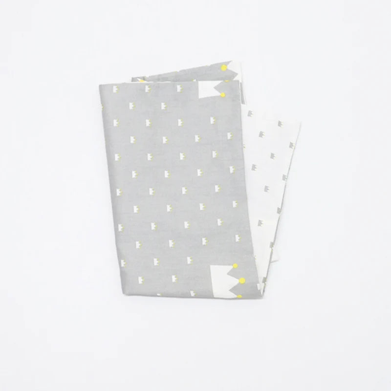 A stack of soft cotton baby pillowcases featuring a light gray background with small yellow cartoon designs.