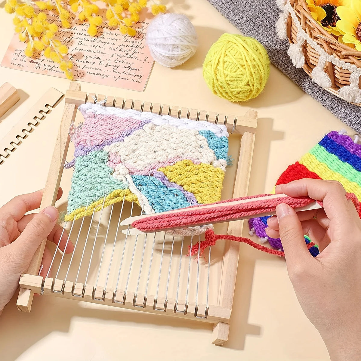Hands are weaving yarn into a wooden loom kit for DIY crafts with colorful threads and wool balls.