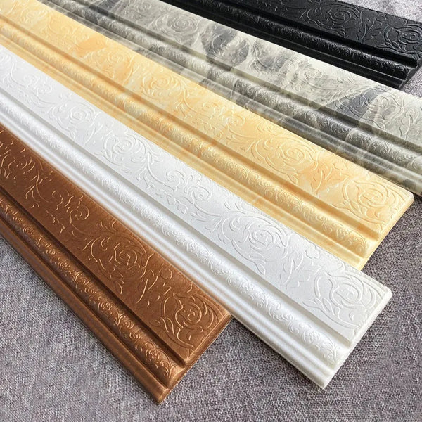Three strips of 3D self-adhesive wall corner and edge trim in gold, white, and black are displayed on a gray surface.