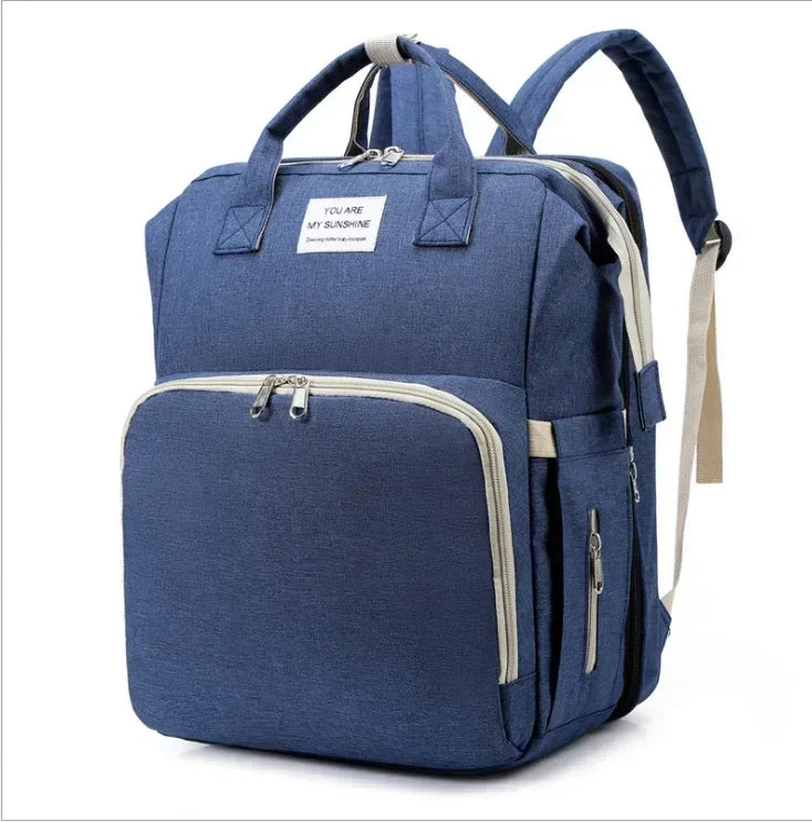 A navy blue backpack diaper bag with a light beige changing mat visible inside.