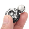 A hand is holding a metal desk spinner, showing its layered design and spherical top.