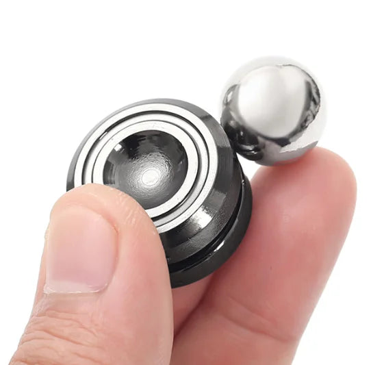 A hand is holding a metal desk spinner, showing its layered design and spherical top.