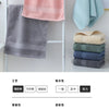 A display of six folded face towels in various shades of gray, pink, and blue on a white rack.