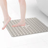 A person's bare foot is placed on a gray non-slip shower mat with suction cups for bathroom floors.