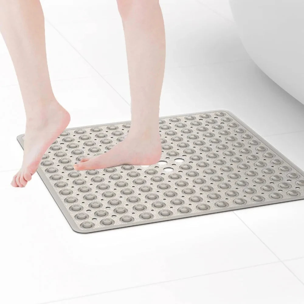 A person's bare foot is placed on a gray non-slip shower mat with suction cups for bathroom floors.