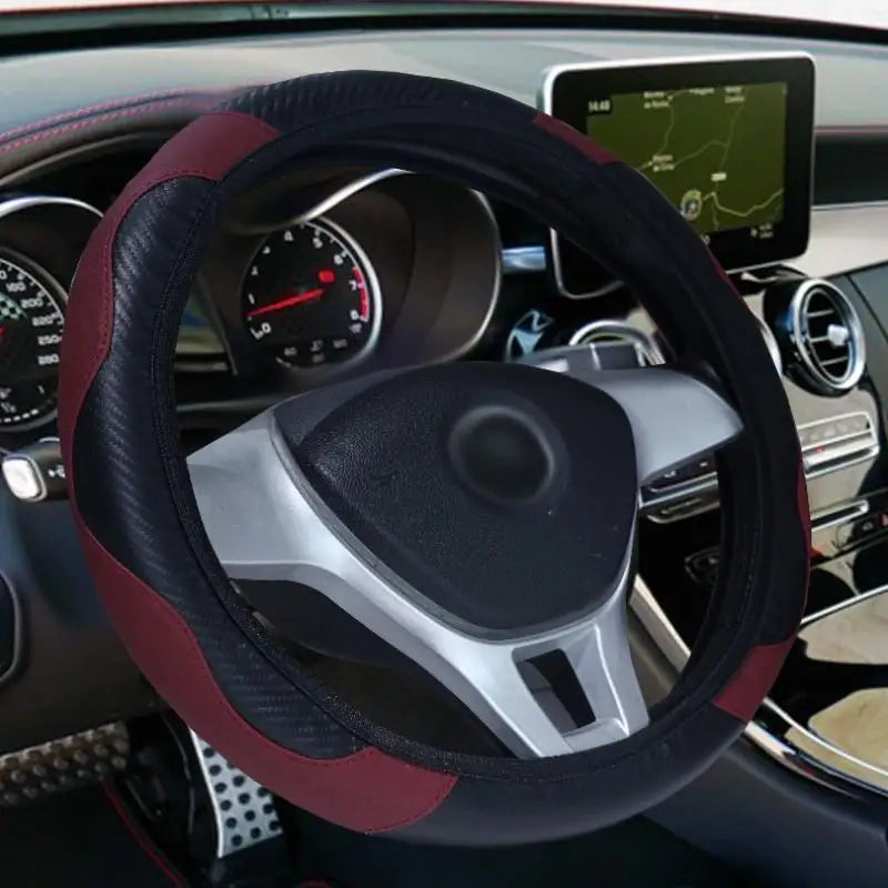 Close-up view of a black steering wheel with a red leather cover and silver grips inside a car interior.