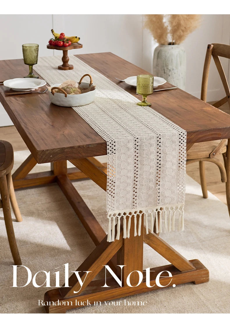 Beige boho table runner with tassels on a wooden dining table.