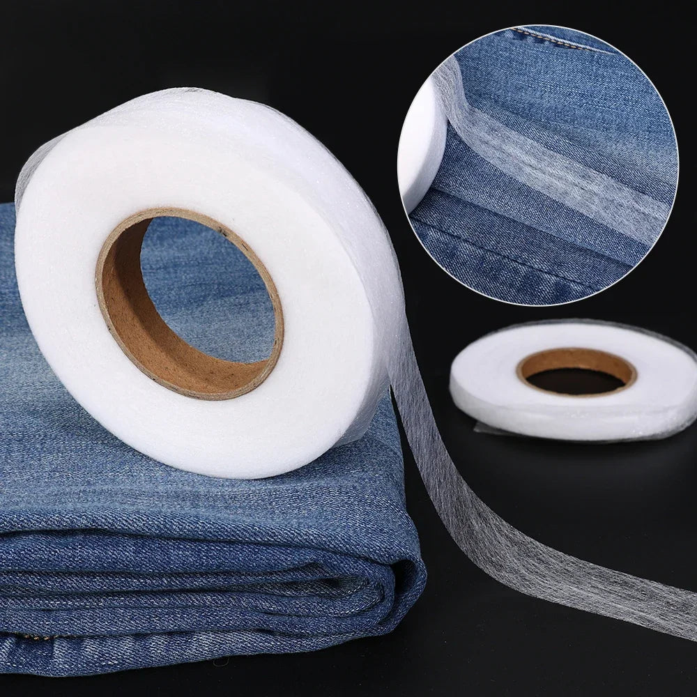 Roll of white double-sided iron-on fabric adhesive tape with a blue denim fabric swatch.