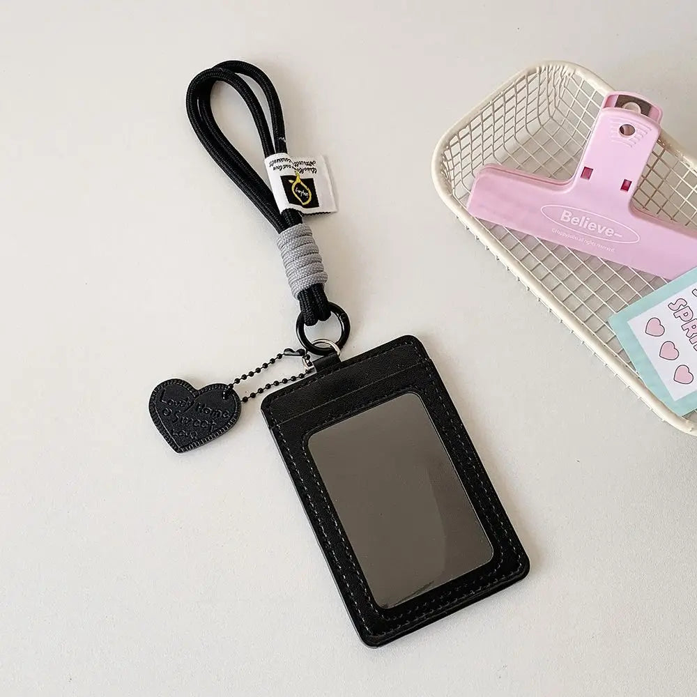 Schwarzes Kunstleder-Kartenetui mit Lanyard und pinkes Plastik-Kartenträger auf einem geflochtenen Korb