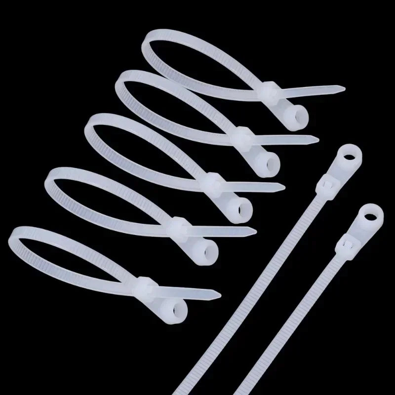 A collection of white reusable screw-hole cable ties with mounting holes arranged against a black background.