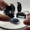 A hand holds a black clip holder device with two labeled slots for garage door remotes.