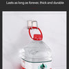A clear plastic bottle of Nongfu Spring water is hanging on a white wall with a metal hook.
