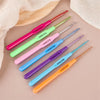 A collection of seven aluminum alloy crochet hooks in various colors and sizes laid out on a light background.