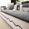 A light gray and white striped chenille sofa cover with a pleated black hem and decorative pillows.