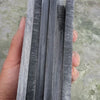 A hand holds a stack of black buffalo horn knife handle scales.