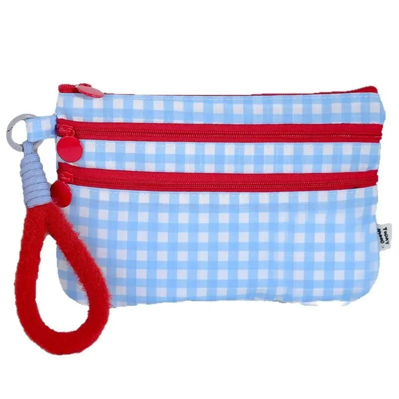 A blue and white checkered passport holder with a red zipper and a red loop.