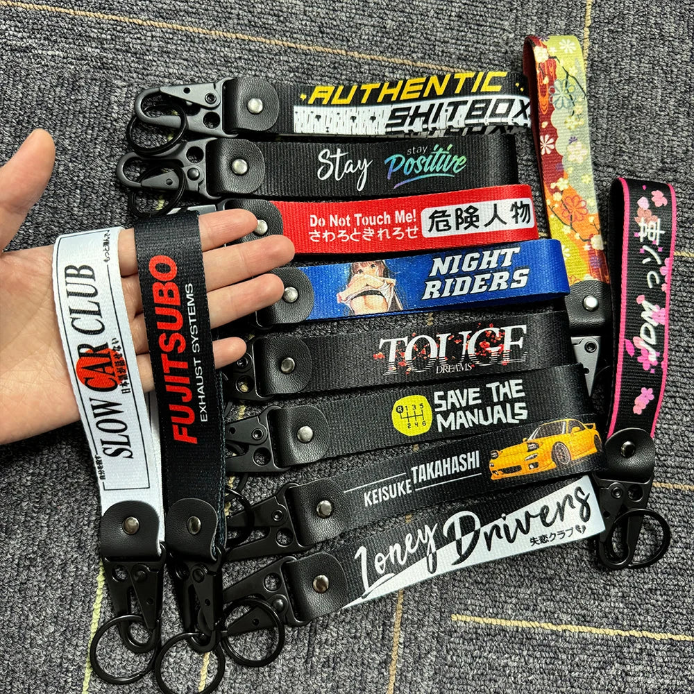 A collection of black and colorful leather keychains featuring various text designs like Stay Positive Night Riders and Save 