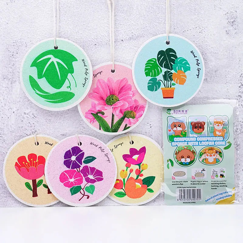 Ten eco-friendly wood pulp dish sponges in various floral designs, including green leaves and pink flowers.